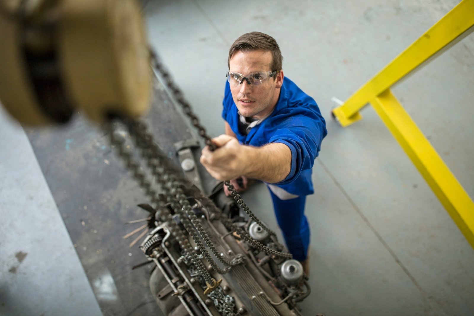 Overhead view of male car mechanic winching car engine in repair garage